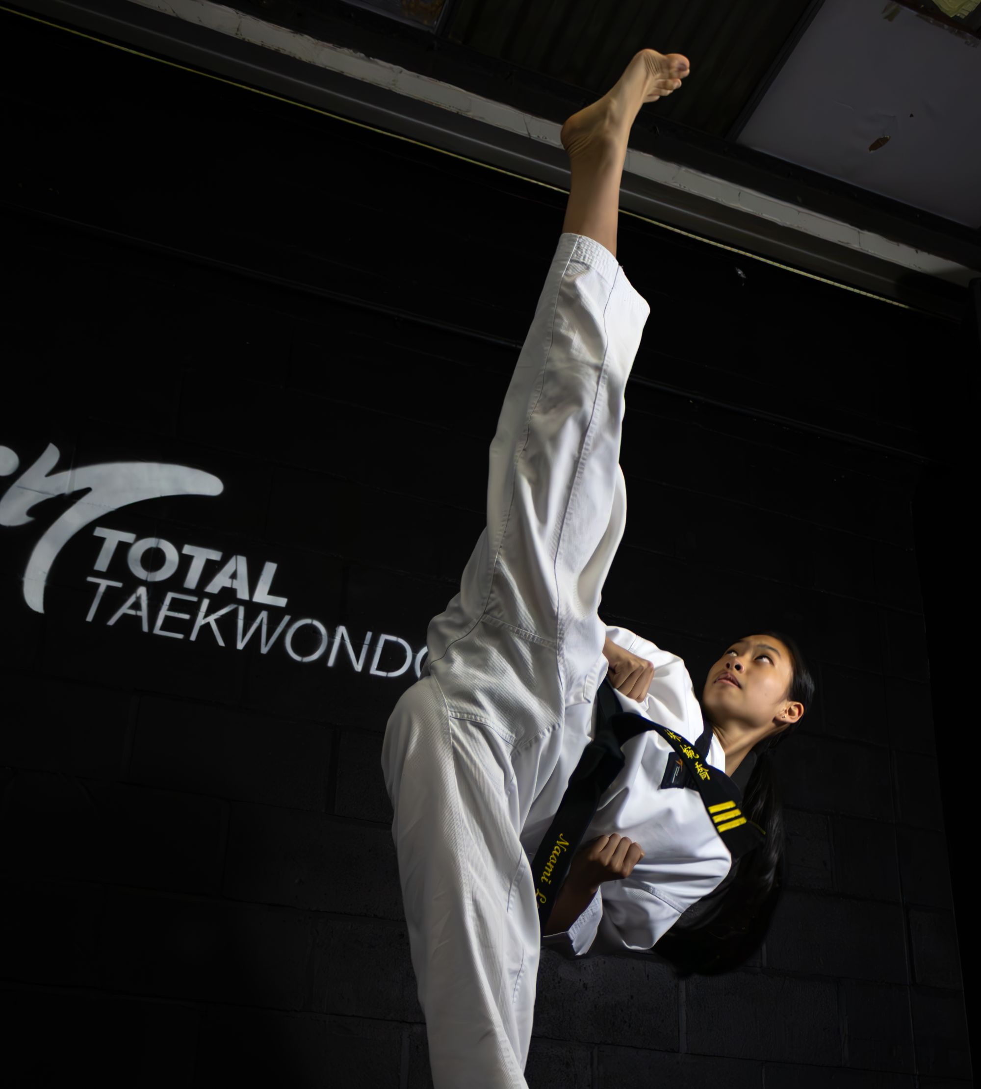 Total Taekwondo black belt performing a head-height kick